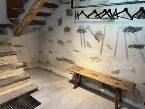 A stone staircase leading to a wooden bench against a textured wall with a metal rack.
