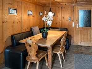 Un interior de madera con una mesa de comedor, sillas, un banco y una planta en maceta.
