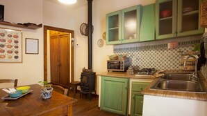 A kitchen with green cabinets, a wood-burning stove, a microwave, and a sink. - beautiful accommodation in a quiet location and with a huge garden, M2 (Pomaia)