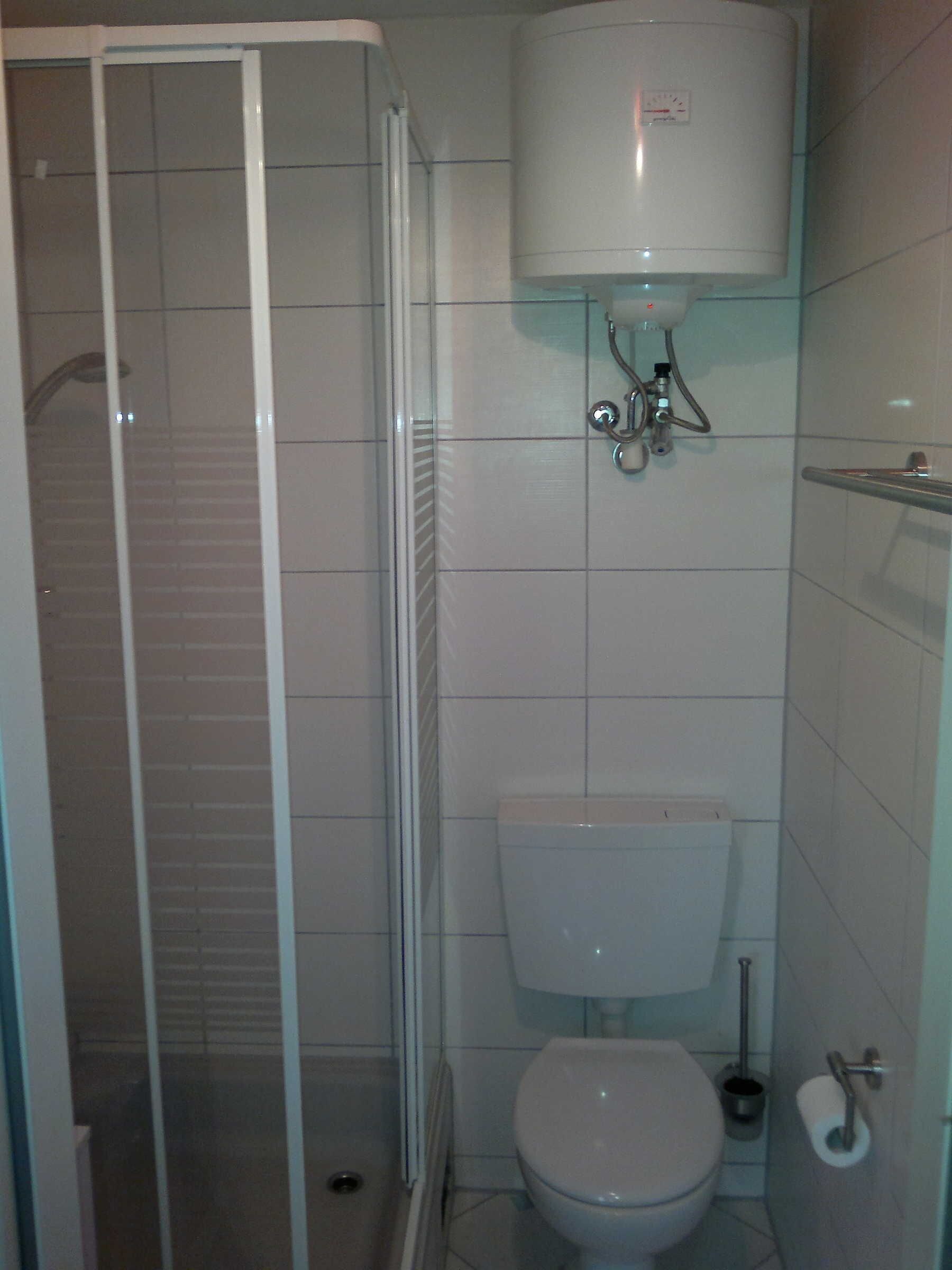 Ein Badezimmer mit Glasdusche, Toilette und WC-Papierhalter.