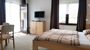 A hotel room with a bed, a television, a desk with a chair, and a wardrobe. - Holidayflat with balcony, seperate entrance, near Thuringian Forest (Floh- Seligenthal)