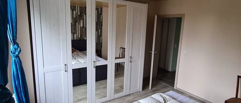 Une chambre avec une armoire, un lit et une chaise.