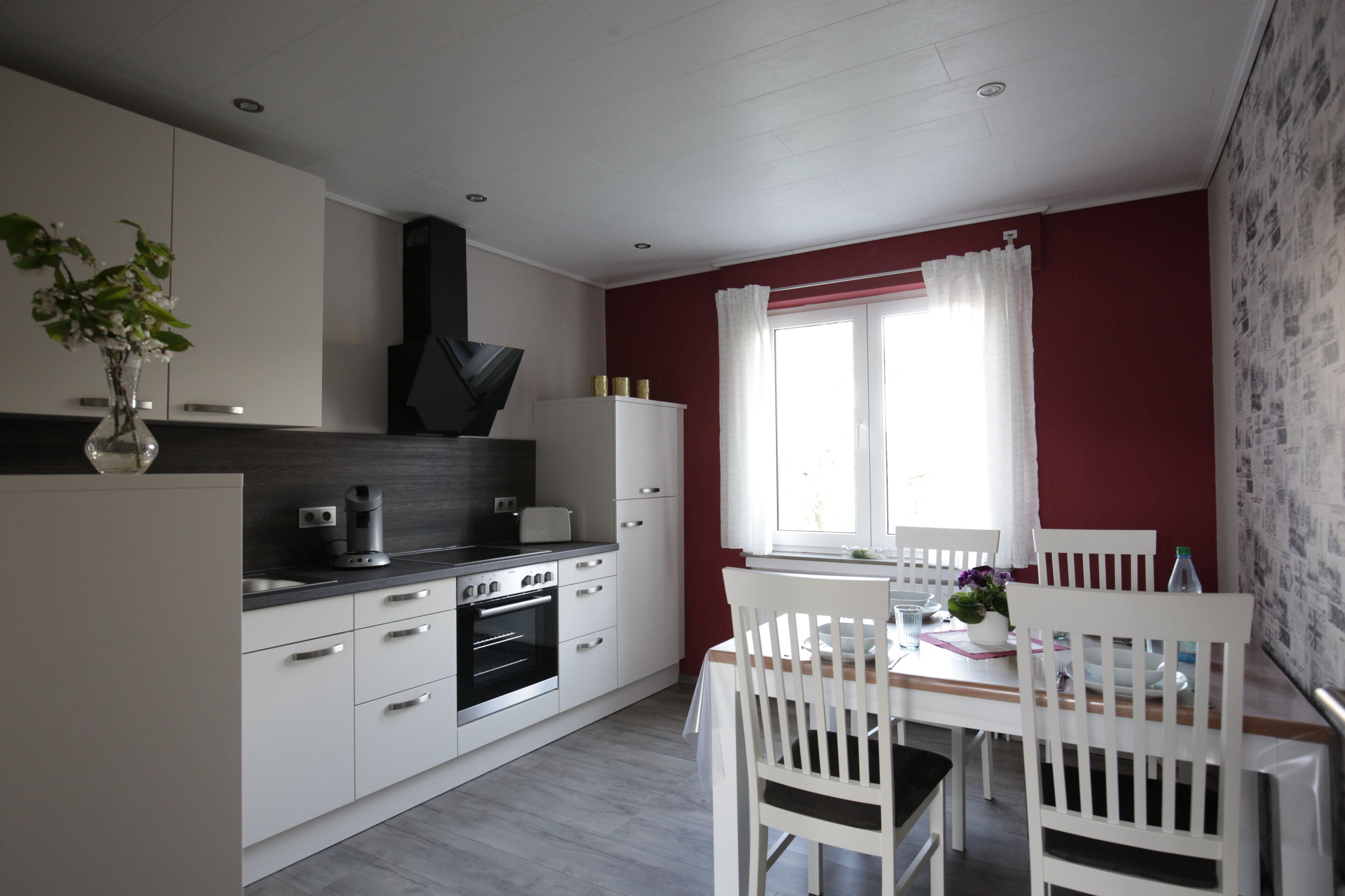 Une cuisine moderne avec des meubles blancs, une cuisinière noire et une table à manger entourée de chaises blanches.