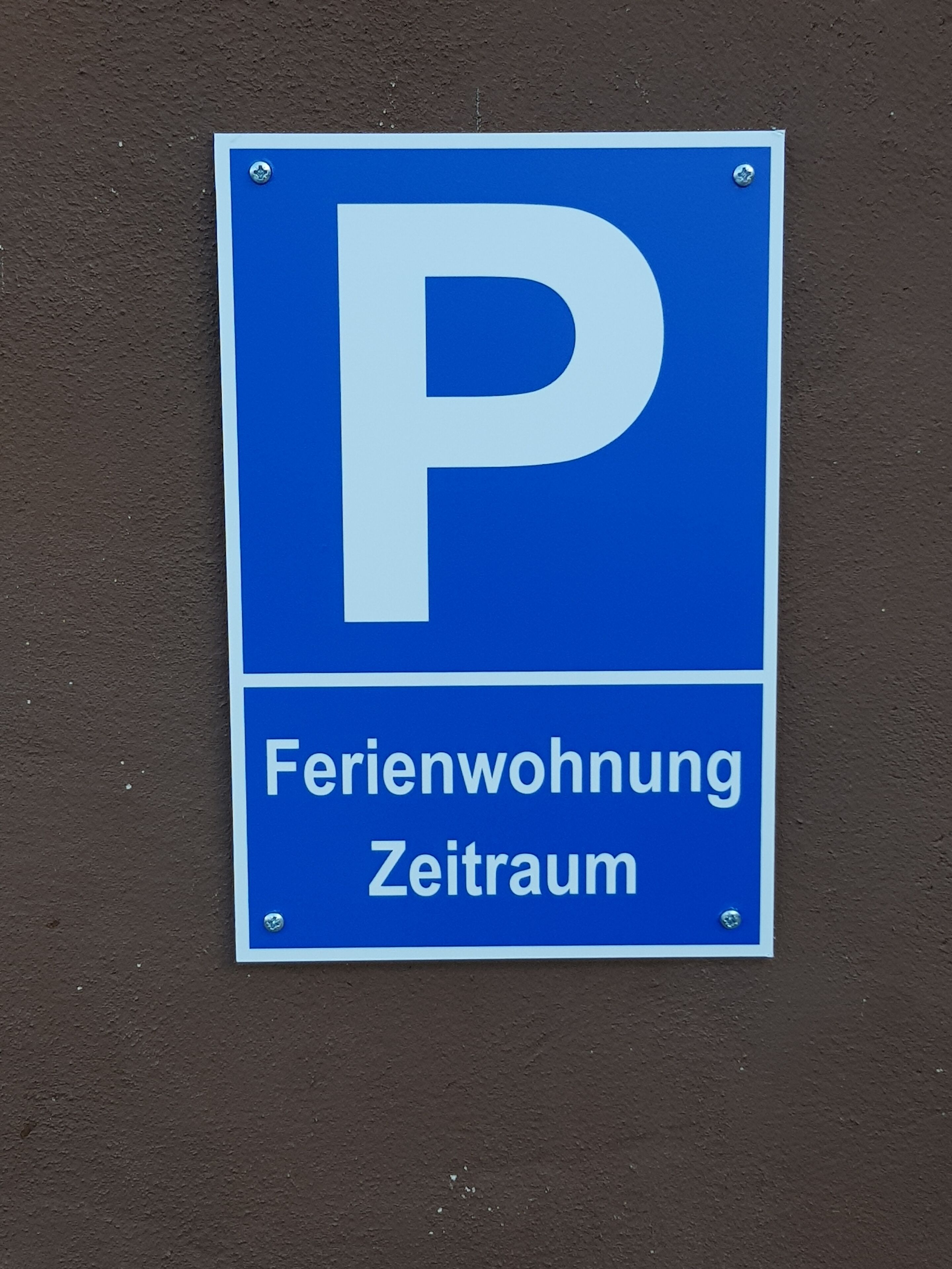 Ein blaues Parkschild mit dem Buchstaben 'P' und dem Hinweis 'Feriendorf' sowie einem Zeitraum.