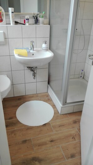 Une salle de bain avec un lavabo blanc, des toilettes et une douche.