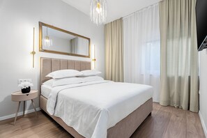 Quarto moderno com uma cama grande, mesa de cabeceira com um vaso de flores, espelho e um candelabro.