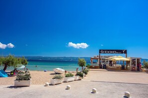 A beach area with a sign reading "SHOOKO BEACH", outdoor seating, and a view of the sea. - BANE Apartments - Holidays with family 70 meters from the sea (Duće)