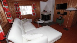 A cozy room with a white sofa, a fireplace, a TV, and a small table. - BEAUTYFULL COTTAGE WITH MOTORBOAT and CANOE (Säffle)