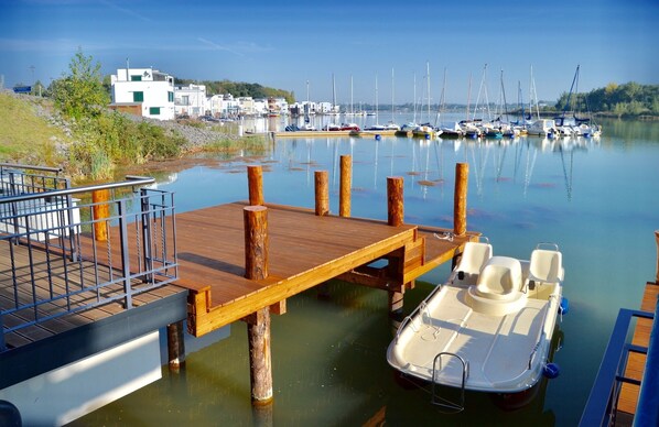 Una marina con barcos amarrados, un muelle de madera y un pequeño bote en primer plano.