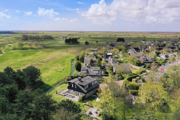 An aerial view of a residential area with houses, green fields, and a clear sky. - Child Friendly, 5 bedrooms, 2 bathrooms, 3 Toillets, Sauna, large garden (Niederlande)