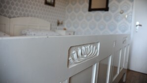 A bedroom with a white headboard, a patterned wallpaper, and a framed picture on the wall.