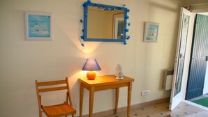 A room with a wooden chair, a small table with a lamp, a mirror, and a door leading to an outdoor area. - Pleasant family villa, in the heart of Cap Ferret, close to the beach, 12 pers (Lège-Cap-Ferret)
