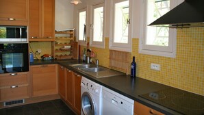 A kitchen with wooden cabinets, a microwave, a dishwasher, and a sink. - Pleasant family villa, in the heart of Cap Ferret, close to the beach, 12 pers (Lège-Cap-Ferret)