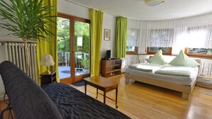 Une chambre à coucher avec un lit, un canapé, une petite table, une lampe et une plante en pot.