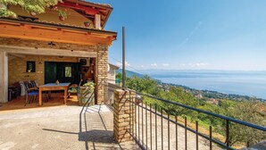 Ein rustikales Steinhaus mit einem Balkon, der einen schönen Blick auf einen See und ferne Berge bietet.