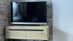 Ein Flachbildfernseher auf einer Holzkabine vor einer Wand mit Steinmusterung.