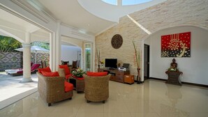 A spacious living area with wicker furniture, a flat-screen TV, and a decorative wall piece. - Luxurious, quiet, private Pool-Villa Lotus, 7/7 housekeeper/butler (Phuket)