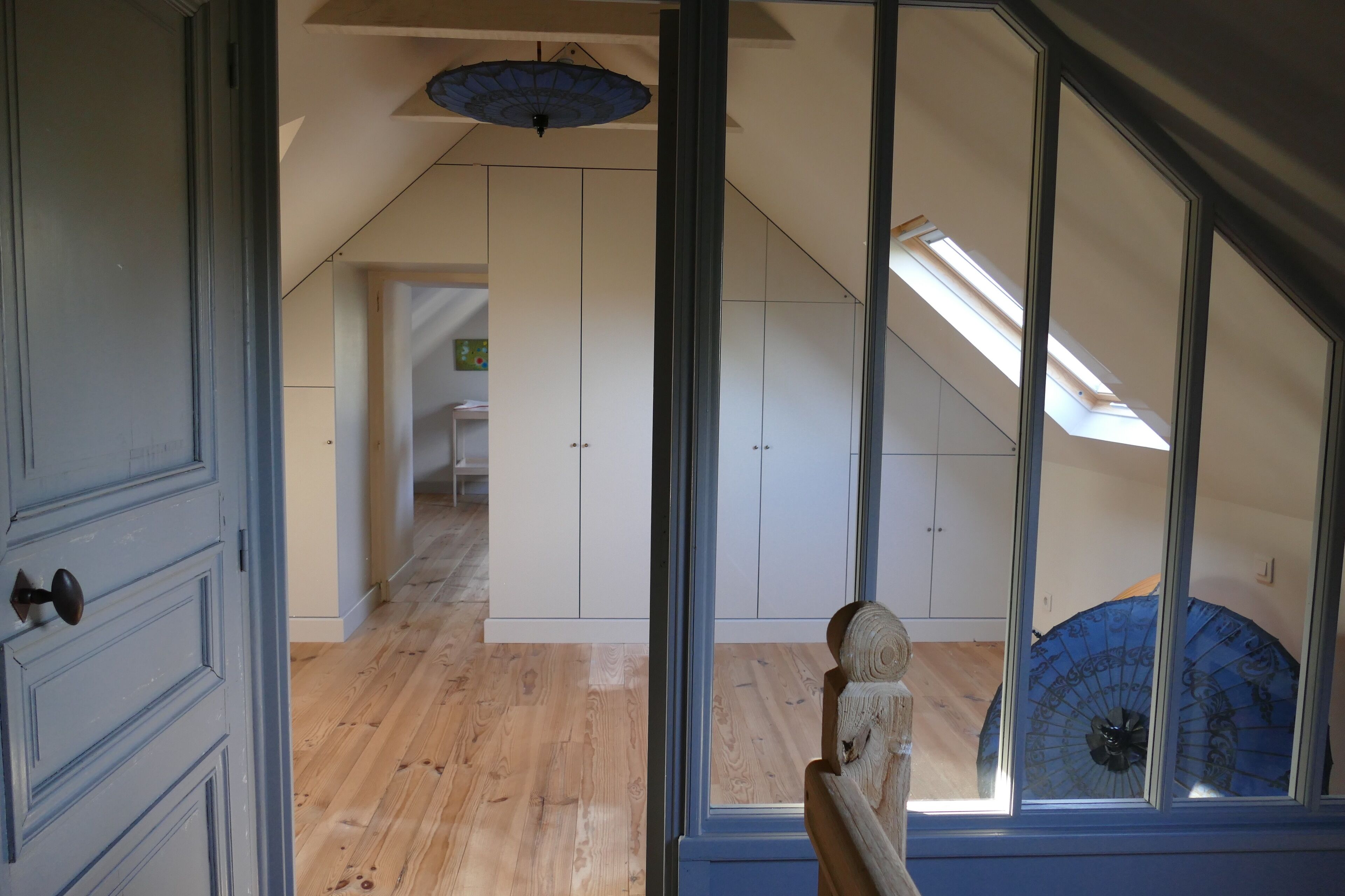 An interior view of a room with wooden flooring, white cabinets, and a skylight.