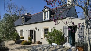 A house with a stone facade, a tiled roof, and a garden with a gravel path. - Exclusively renovated farmhouse in southern Brittany (Fouesnant)