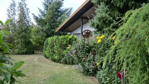 Un jardín con una estructura de madera, rodeado de diversas plantas y flores.