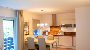 A modern kitchen with a dining area, wooden cabinets, and a chandelier.