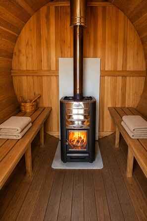 A wood-burning stove in a wooden room with benches and a bench seat.