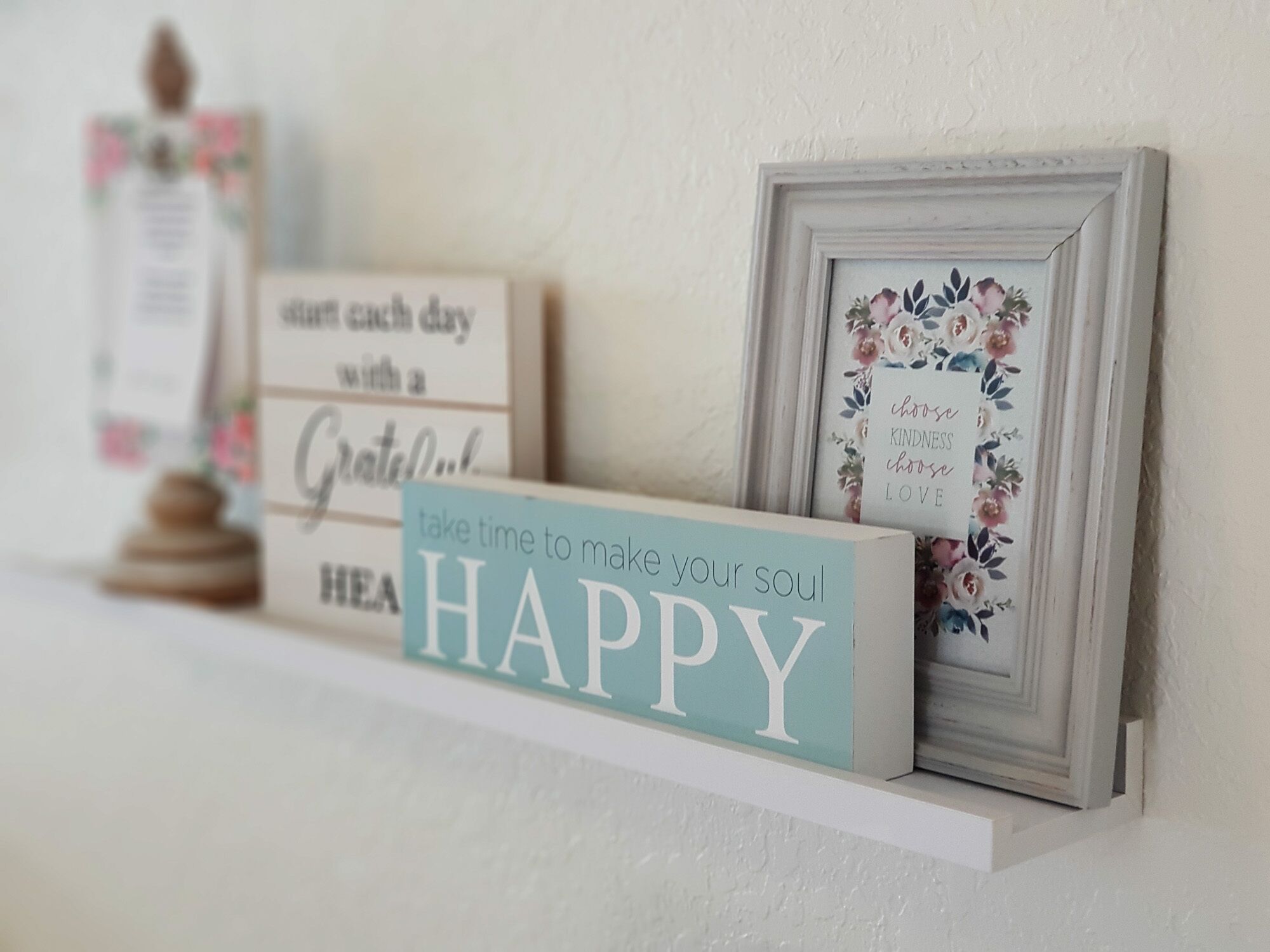 A shelf with motivational signs and a framed picture.