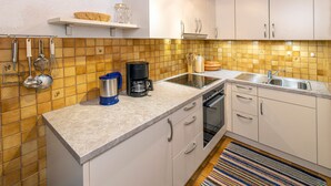 A kitchen with white cabinets, a coffee maker, and a sink. - Apartment A (2-3) - Apartments and Bed & Breakfast Eberle (Jungholz)