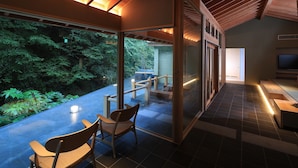 A modern interior with a glass wall, wooden ceiling, and a view of a forest.