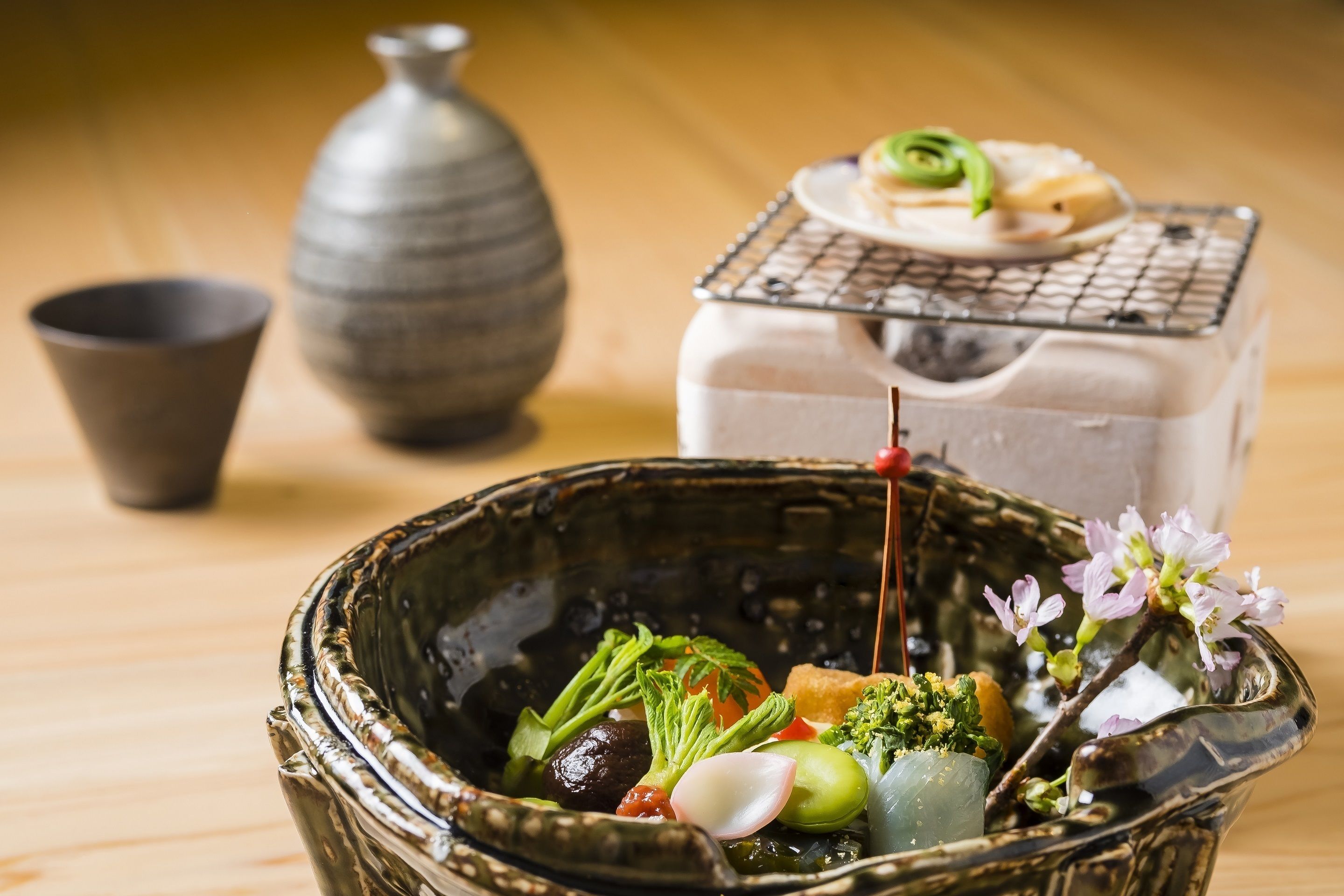A traditional Japanese meal with various vegetables and a small dish on a wire rack.