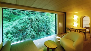 A modern interior with a large window, a round table, a sofa, and a chair.