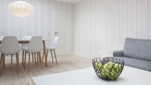En moderne stue med spiseplads, der indeholder en hvid sofa, en grå sofa og et spisebord med stole.