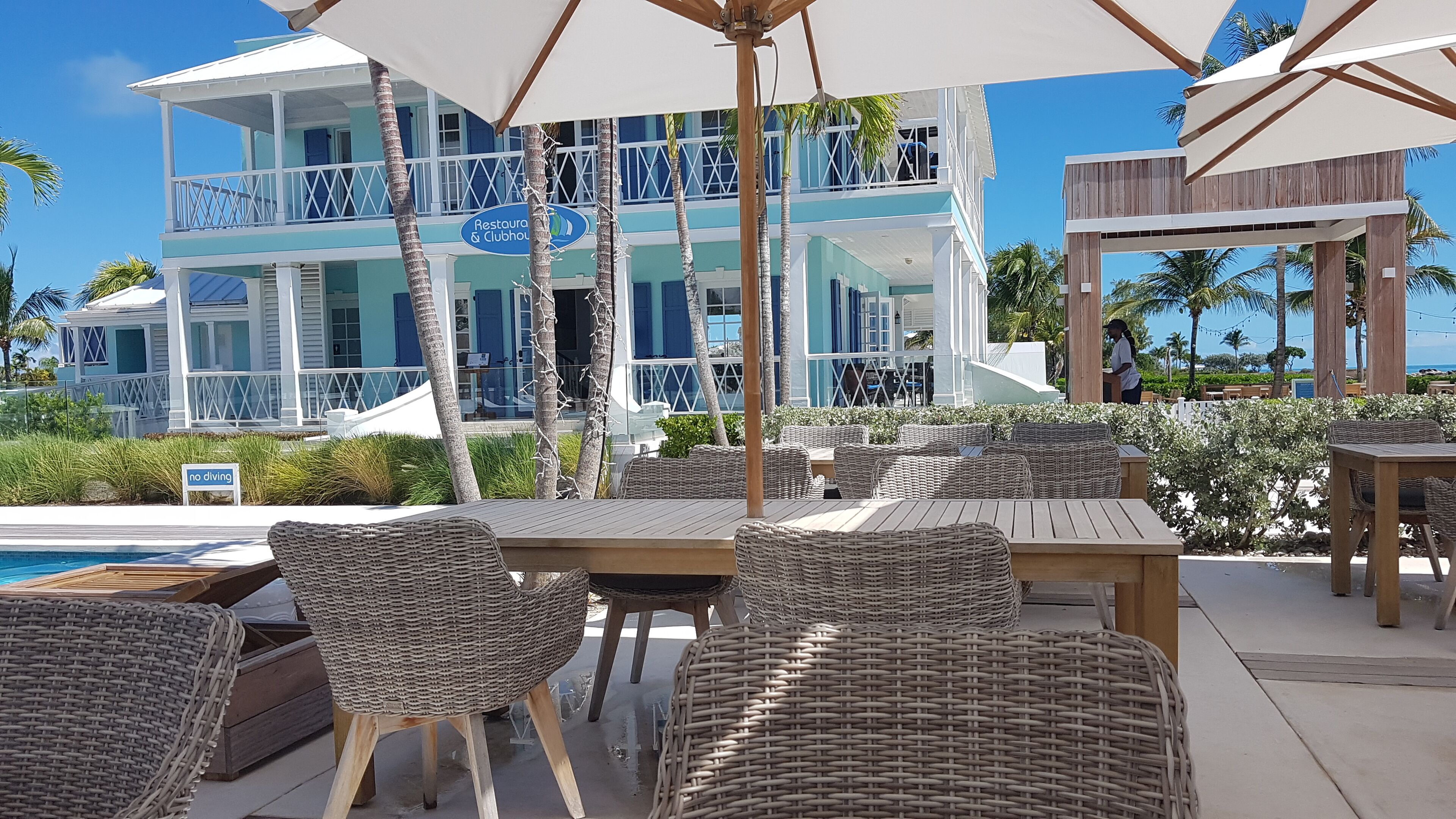 Un resort con asientos al aire libre, una piscina y un edificio con un letrero que dice 'Restaurant & Clubhouse'.