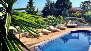 A swimming pool with lounge chairs, surrounded by greenery and a clear sky. - Villa with pool and view in Luz/Lagos (Luz)