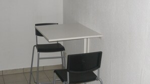 Una habitación pequeña y sencilla con una mesa blanca y dos sillas negras.