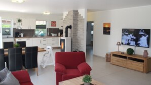 Una sala de estar moderna con un sillón rojo, una mesa de centro de madera y un televisor.