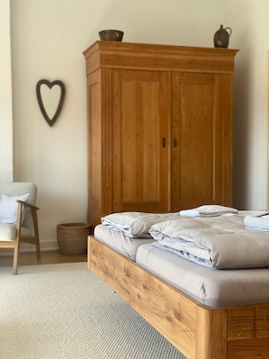 Une chambre à coucher avec un lit en bois, une chaise, un panier et une armoire en bois.