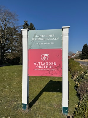 A sign with text indicating a location for 'Gastezimmer' and 'Ferienwohnungen' with a green and red color scheme.