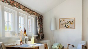 Una habitación con suelo de madera, una mesa de comedor con sillas, una lámpara y un cuadro en la pared.