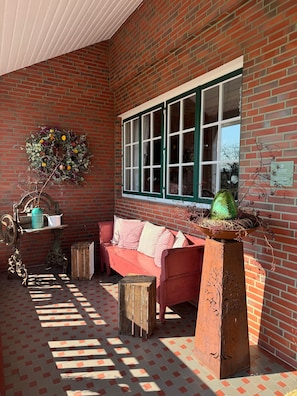 A brick-walled room with a red sofa, a green window, and a decorative wreath.
