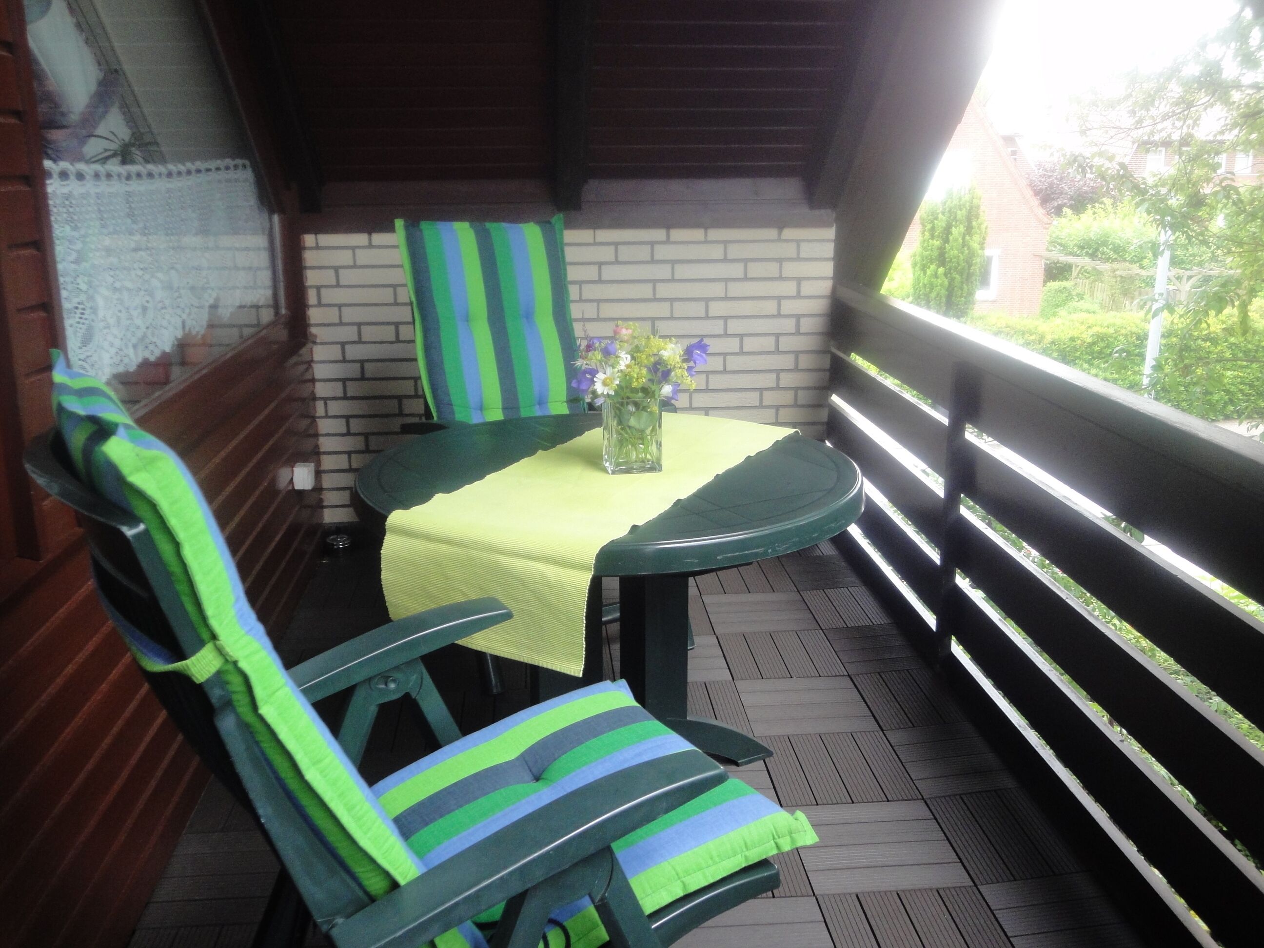 Un espace extérieur abrité, avec une table et des chaises, un mur en briques et une vue sur la verdure.