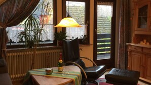 Una habitación acogedora con una mesa de madera, un sillón de cuero negro, un taburete pequeño y un radiador.