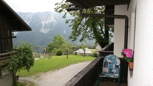 A balcony with a view of mountains, a wooden fence, and a chair with a patterned cushion. - Vacation apartment - mountain farm "Pr Tic" 1050m. Nature, peace, air! 25 km from Bled (Tržic)