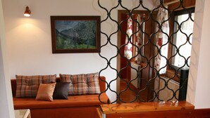 A wooden dining table with a lace tablecloth and a potted plant. A wooden bench and a cushioned seating area are visible in the background. - Vacation apartment - mountain farm "Pr Tic" 1050m. Nature, peace, air! 25 km from Bled (Tržic)