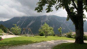A park with a swing set, a tree, and a mountain backdrop. - Vacation apartment - mountain farm "Pr Tic" 1050m. Nature, peace, air! 25 km from Bled (Tržic)