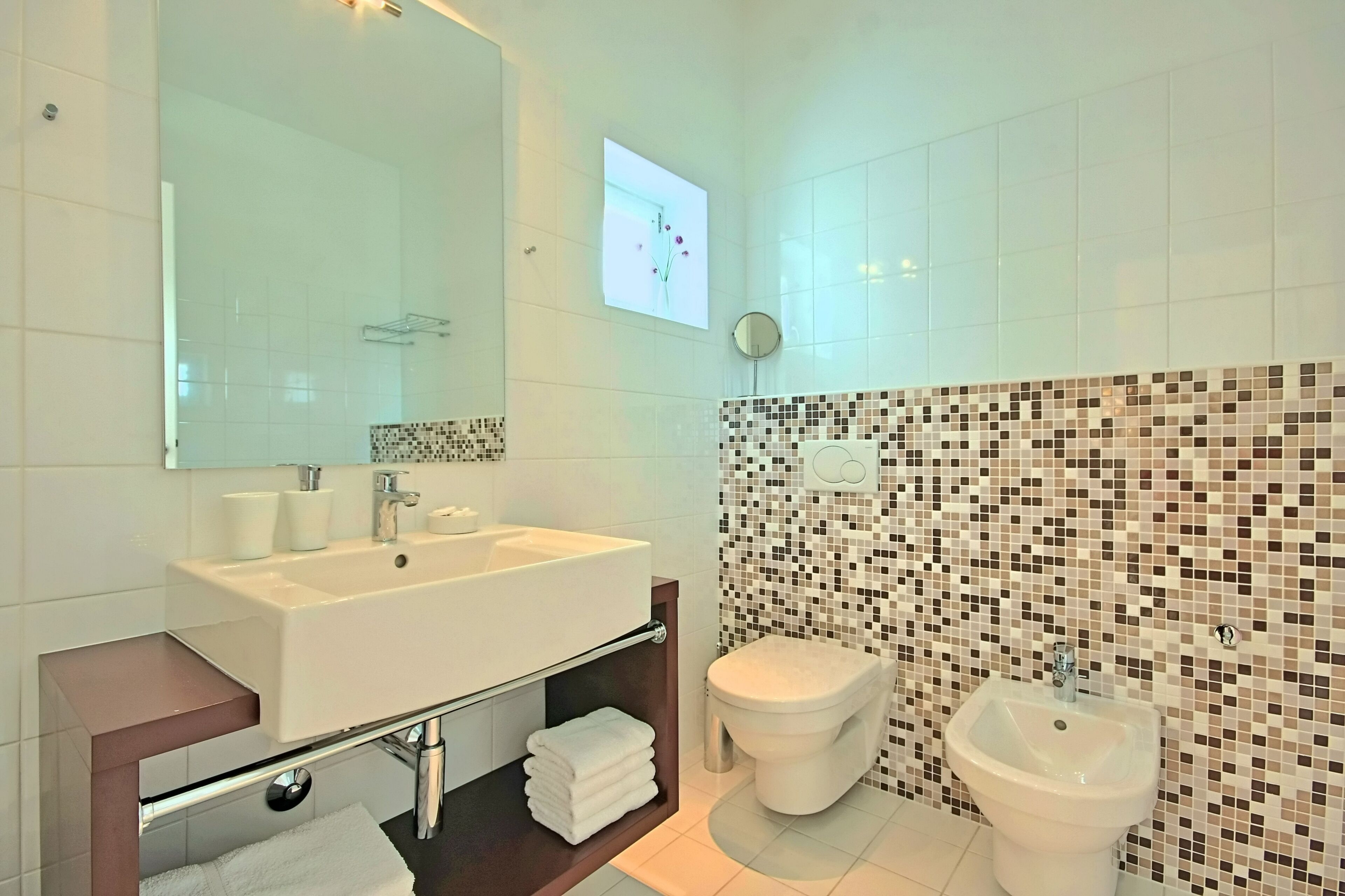 Ein modernes Badezimmer mit einem großen Waschbecken, einer Toilette und einem Bidet.