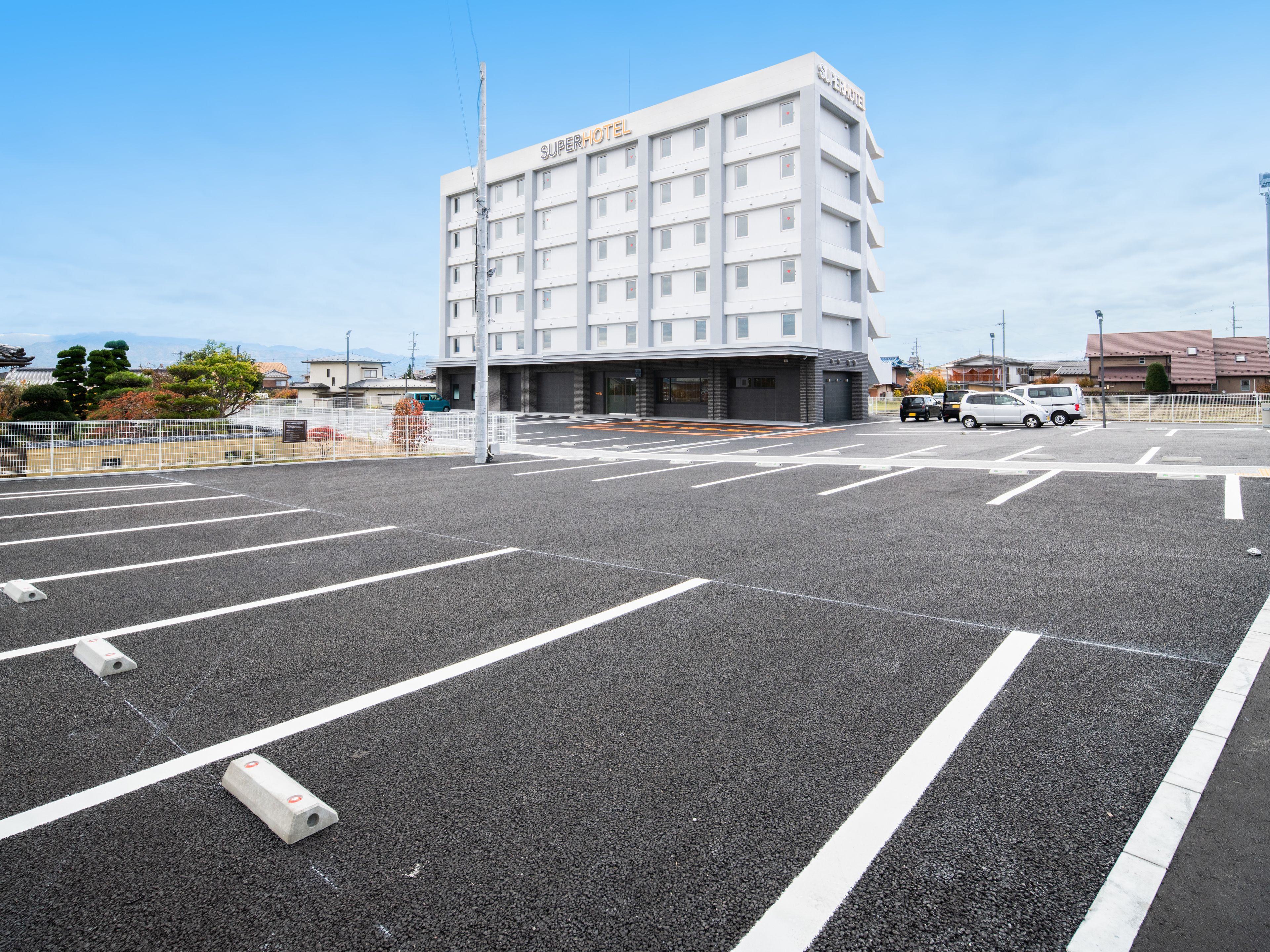 Un hôtel de luxe doté d’une architecture moderne, d’un parking avec des places délimitées et d’un ciel dégagé.