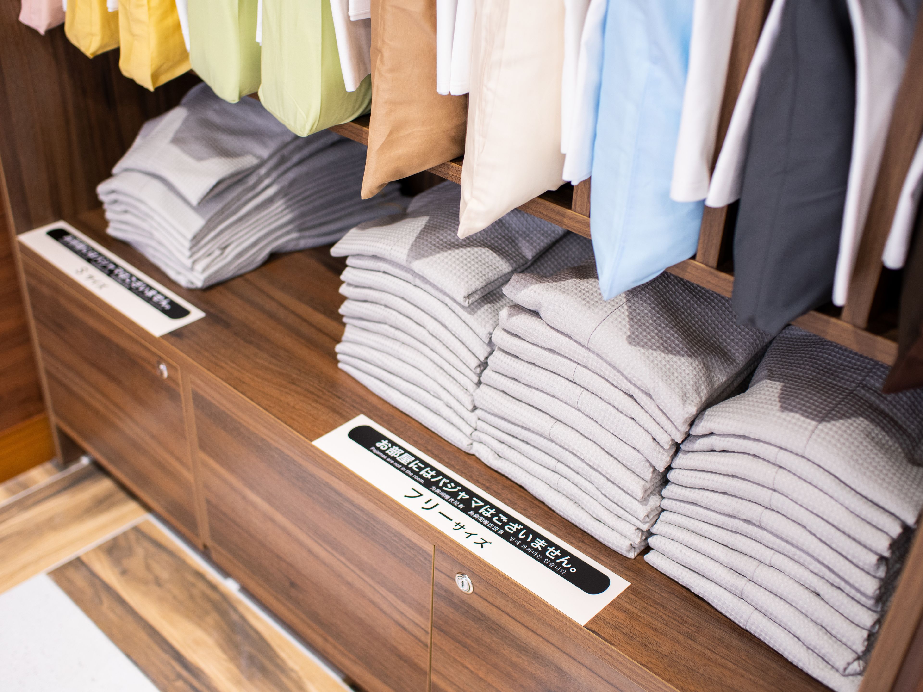 A display of folded towels in various colors on a wooden shelf.