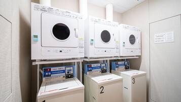 Een wasserette met drie wasmachines, elk met een bedieningspaneel en een digitaal scherm.