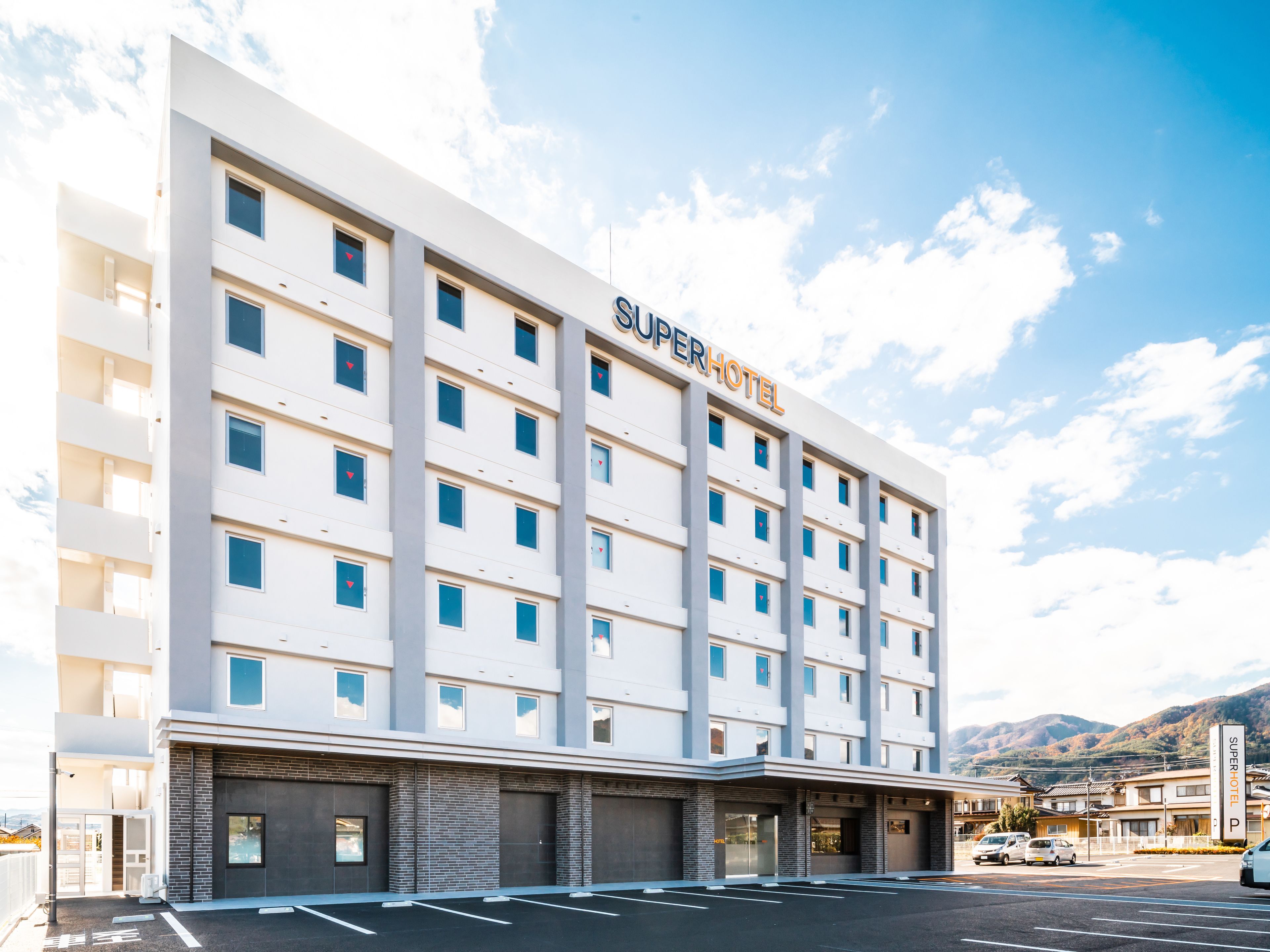A multi-story hotel with a modern design, featuring a prominent 'Super Hotel' sign on the facade.